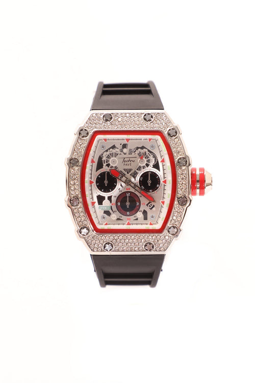 A luxury wristwatch with a silver-tone rectangular case encrusted with clear stones, featuring a skeleton dial with red accents and a black rubber strap, shown against a plain white background.