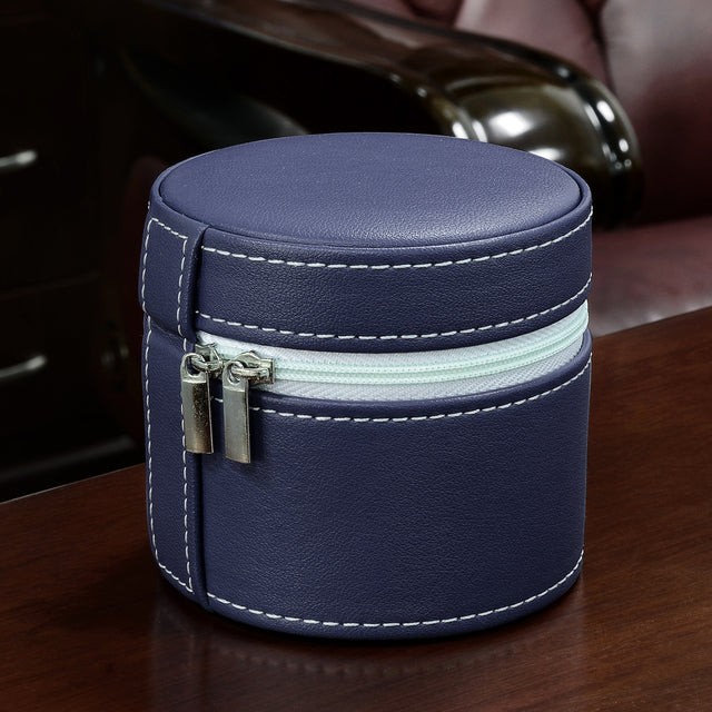 A navy blue faux leather cylindrical case with white contrast stitching and a light blue zipper, shown on a dark wooden table with a blurred background.