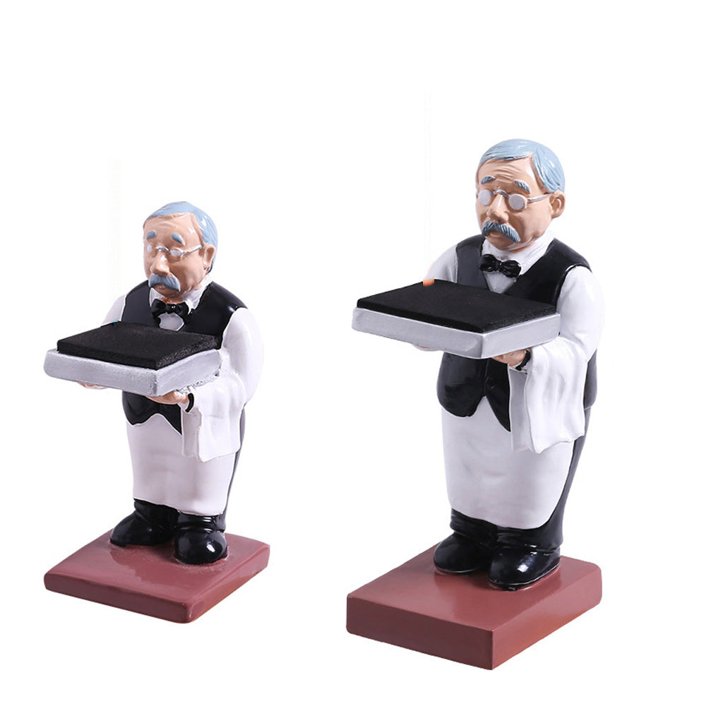 Two decorative figurines of waiters holding black trays, dressed in white shirts and black vests, standing on reddish-brown bases against a white background.